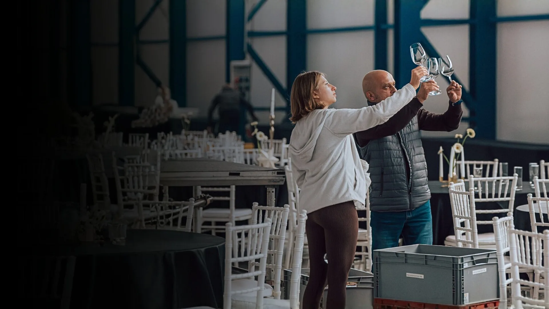 Two members of the Precise team checking glasses against the light while setting up an event